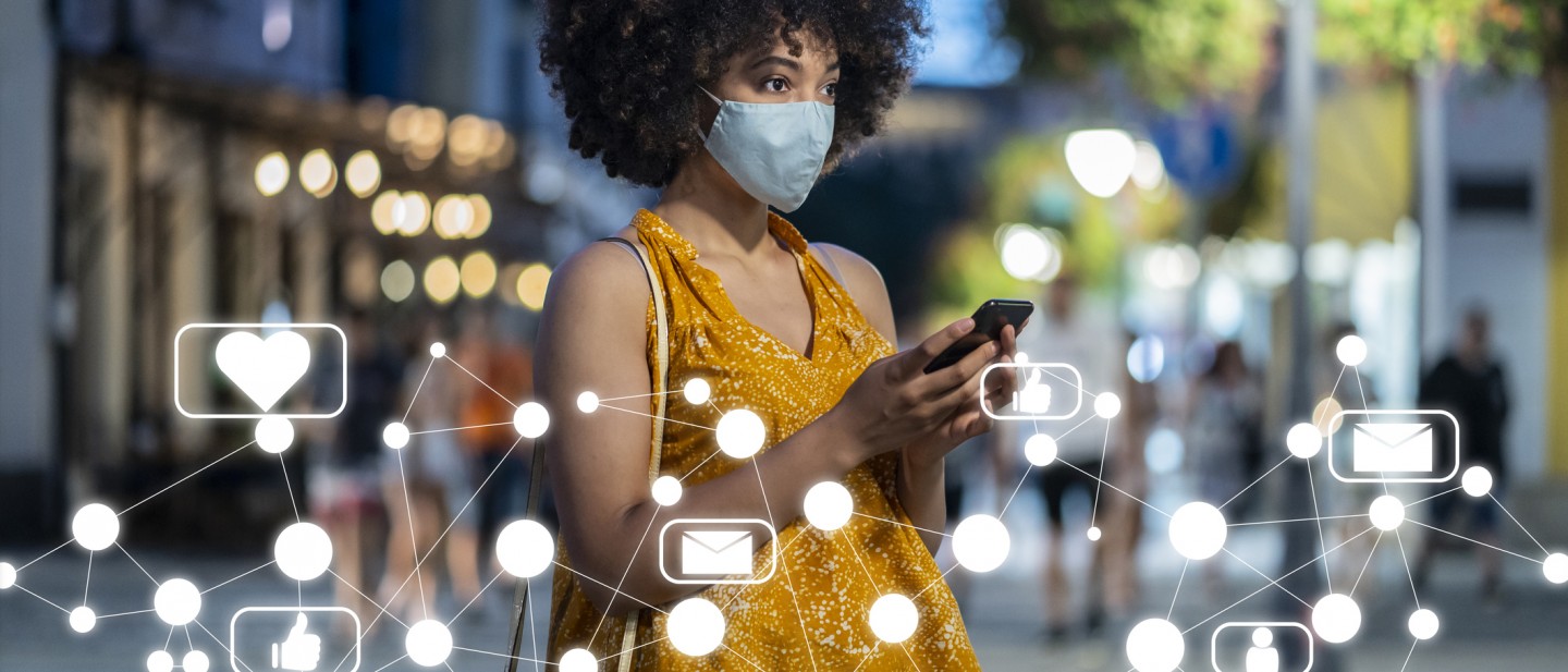 Young Afro-American woman wearing protective face mask using smart phone. Social media concept.
