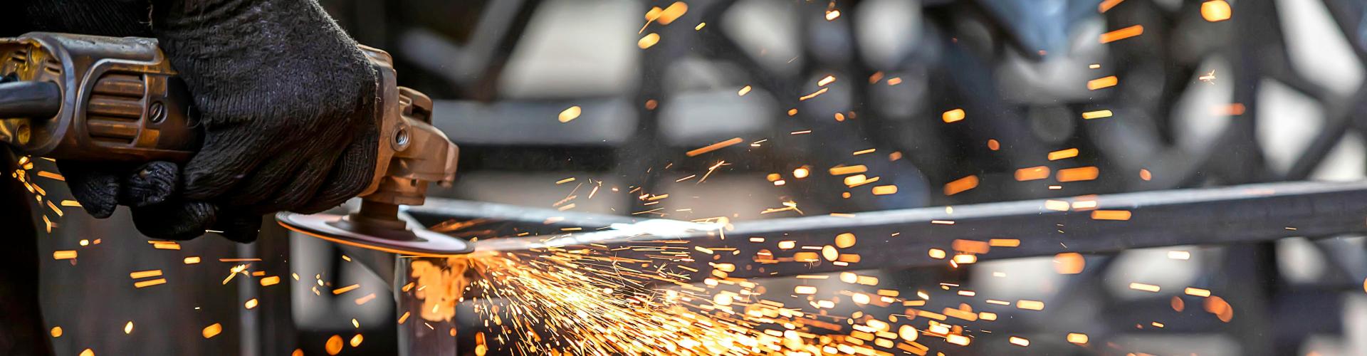 A person using an angle grinder on steel creating sparks